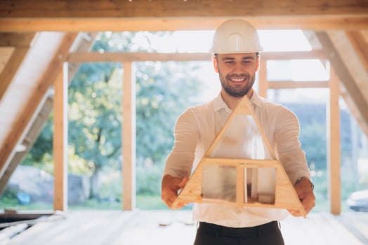 Man builder. Contractor for construction company. Architect in unfinished building. Builder in wooden modular house under construction. Male engineer holding a model of a miniature wooden house photo