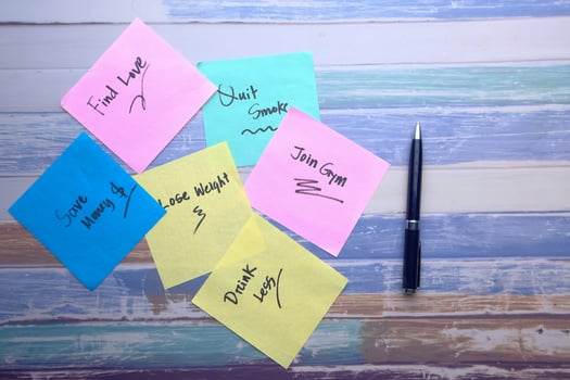Colorful Sticky Notes with Handwritten Messages and a Pen on a polished Wooden Desk photo
