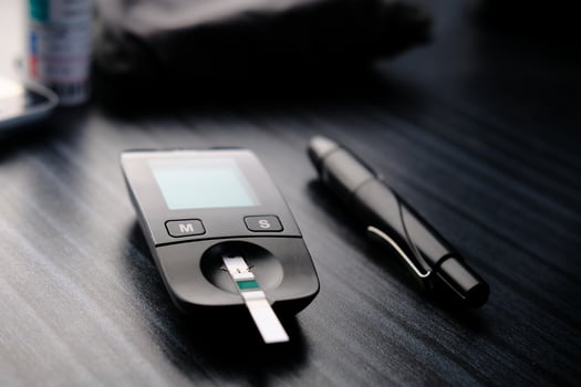 Here is a Diabetes Monitoring Device featuring a Test Strip and Pen placed on the Table photo