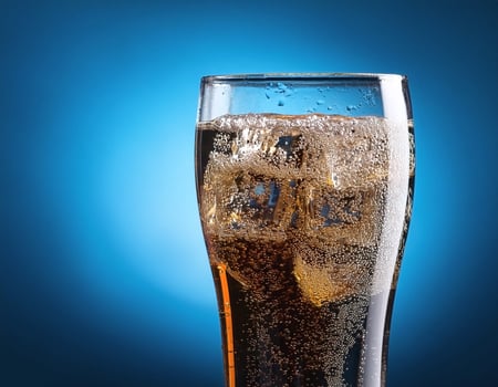 Carbonated soda glass on blue background photo
