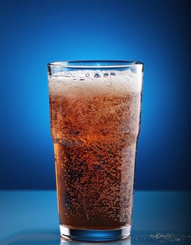 Carbonated soda glass on blue background photo