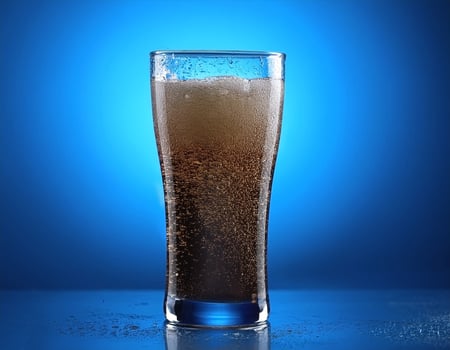 Carbonated soda glass on blue background photo