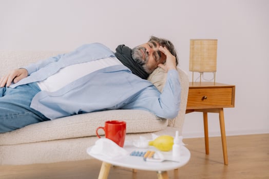 Sick senior male patient lying on the couch at home photo