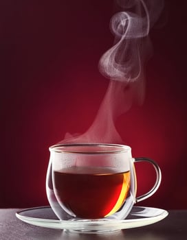 Tea cup with steam, on maroon background photo