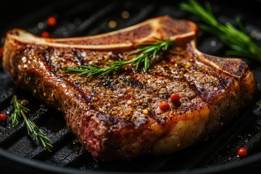 Juicy grilled t-bone steak with rosemary resting on grill pan photo