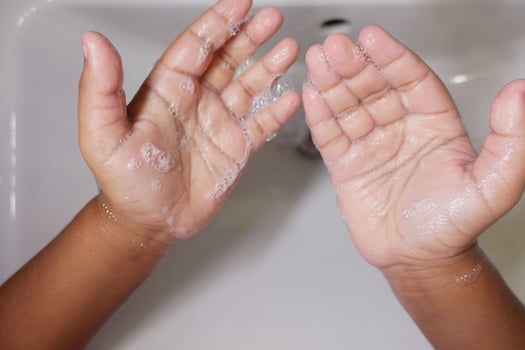 child making a cleansing gesture with soap and water on hands photo