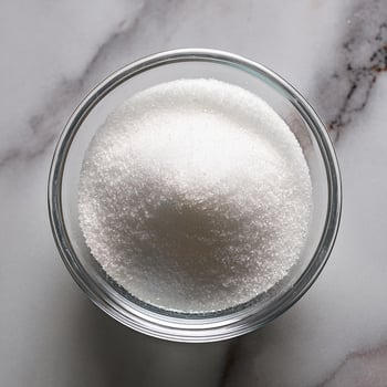 Granulated sugar in a glass bowl on a marble background photo