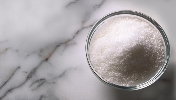 Granulated sugar in a glass bowl on a marble background photo