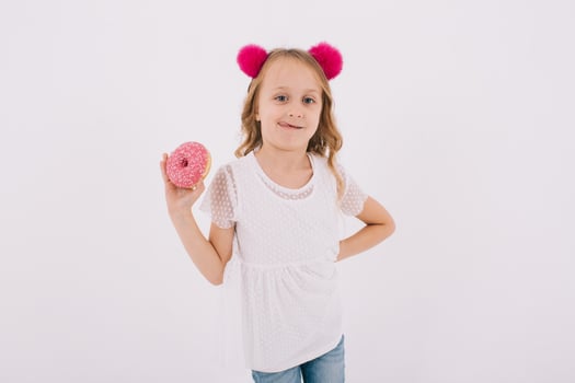 Funny little girl eating a donut on a white background photo