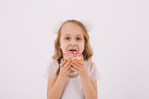Funny little girl eating a donut on a white background photo
