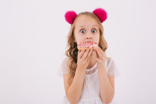 Funny little girl eating a donut on a white background photo