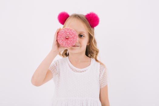 Funny little girl eating a donut on a white background photo