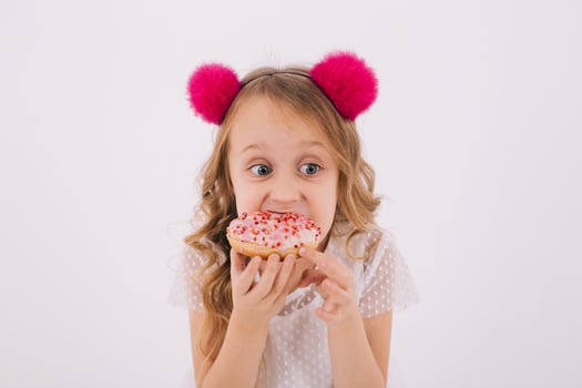 Funny little girl eating a donut on a white background photo