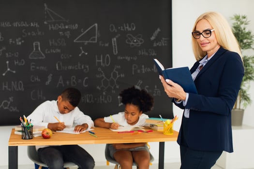 Portrait of female teacher standing on the background of a classroom and school children. photo