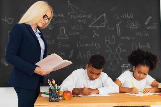 A female teacher teaches school children who sitting at a desk and solving problems. International team. Back to school. photo