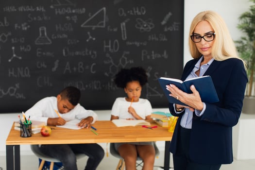Portrait of female teacher standing on the background of a classroom and school children. photo