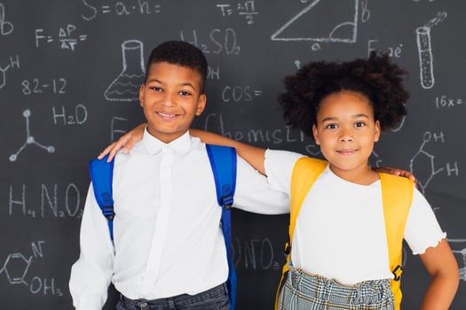 Happy African American schoolgirl and schoolboy solving problems near school board, back to school concept photo