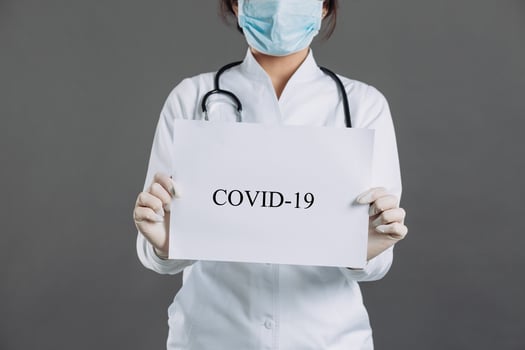 Female doctor with stethoscope in mask holding blank of paper for copy space. photo