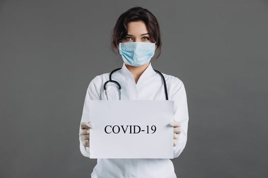 Female doctor with stethoscope in mask holding blank of paper for copy space. photo