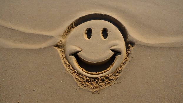 A smiley face is drawn in the sand photo