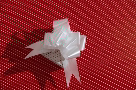 Gift Box with White Bow on Red Polka Dot Background photo