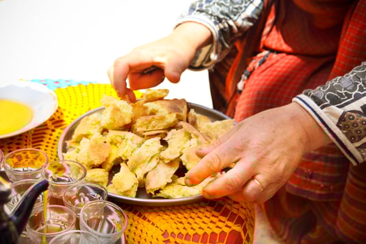 Bedouin woman wearing traditional clothing preparing bread photo