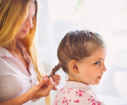 Mother hairdressing her preteen daughter at home photo