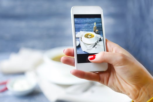 Woman taking a photo of fish soup with smartphone