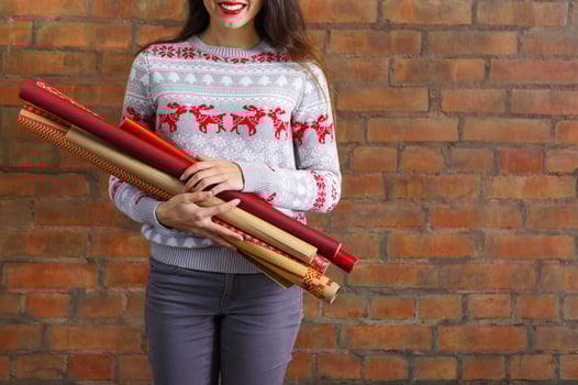 Young woman holding hands closeup wrapping kraft paper rolls for gifts photo
