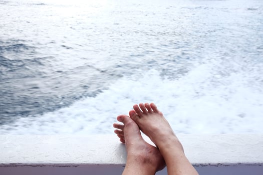 Close up woman feet relaxing on the boat and happy with blue calm sea and wave sponge for vacation and destination on summer photo