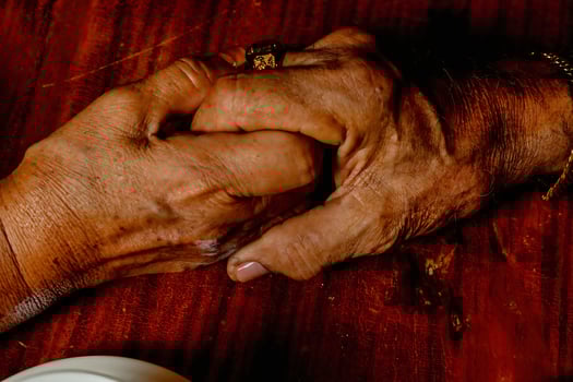 An elderly couple holding hands on a table photo