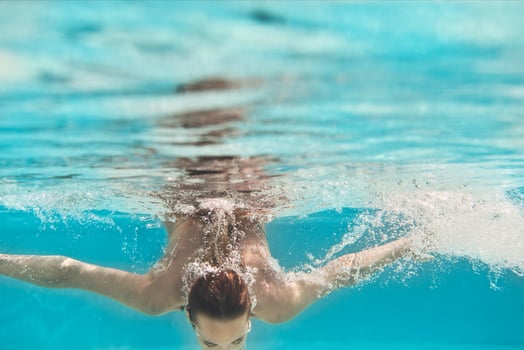 Swimming young woman underwater in pool photo