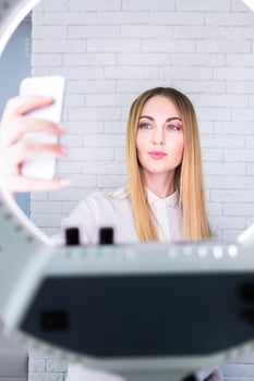 Young and beautiful woman taking selfie with mobile phone in light of the ring lamp photo