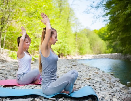 Two women are practicing yoga by the mountain river photo