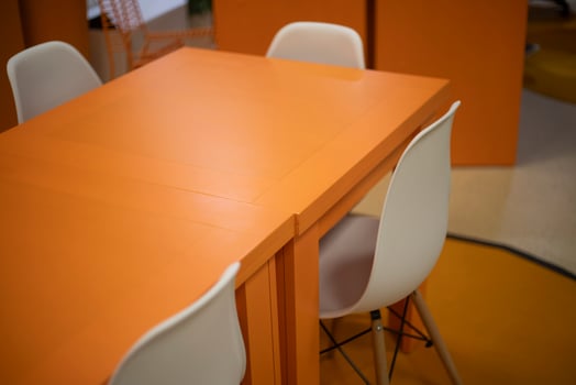 Orange table in the interior. A place to learn. White chairs. photo