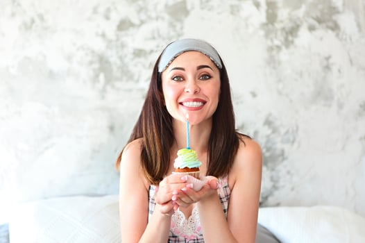 Pretty woman in the sleaping mask holding her birthday cupcake photo
