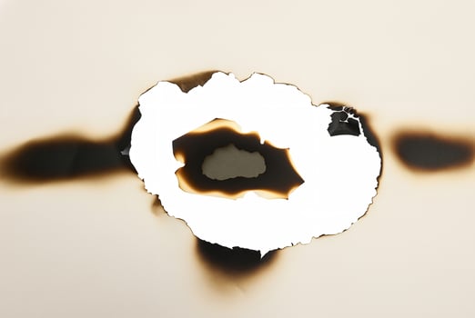 Paper with a burnt hole and charred edges, isolated on a white background, ideal for creative or design projects. photo