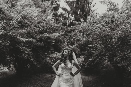 A woman in a wedding dress stands in a forest photo
