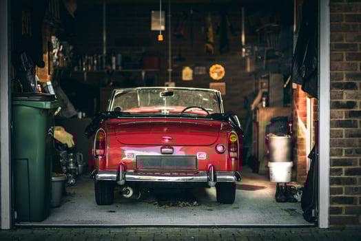 Little red classic Austin Healy parked up in a tight garage in evening sunlight. photo