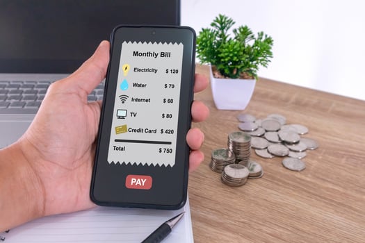 Hand holding a smartphone to pay the monthly bills or household expenses photo