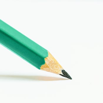 a green pencil is sitting on top of a white surface photo