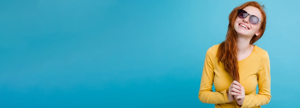 Portrait of happy ginger red hair girl with freckles smiling looking at camera. Pastel blue background. Copy Space photo
