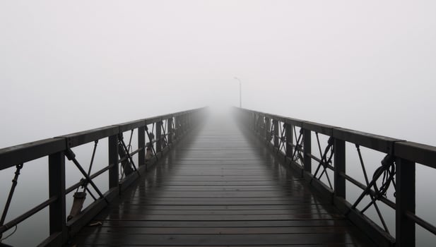 A dimly lit bridge amidst the foggy landscape photo
