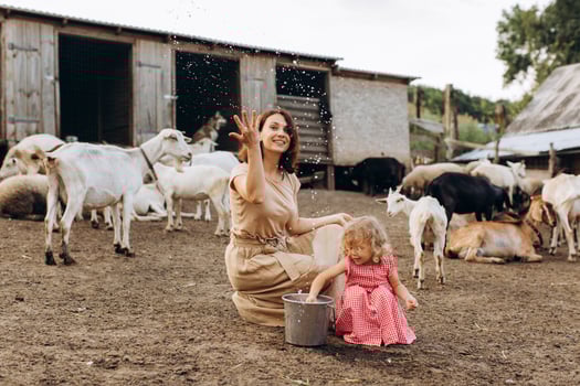 Happy mother and her daughter spend time on an eco farm among goats. photo