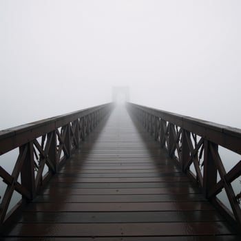 A dimly lit bridge amidst the foggy landscape photo