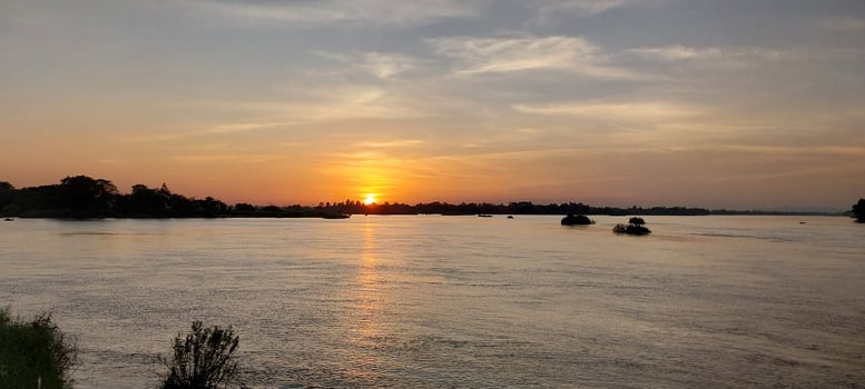 Tranquil sunset over a serene river with distant boats and a peaceful horizon, perfect for nature and travel themes. photo