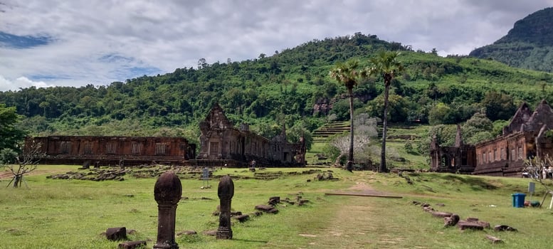 Ancient temple ruins surrounded by lush green hills under a cloudy sky, showcasing historical architectural beauty and natural landscapes. photo