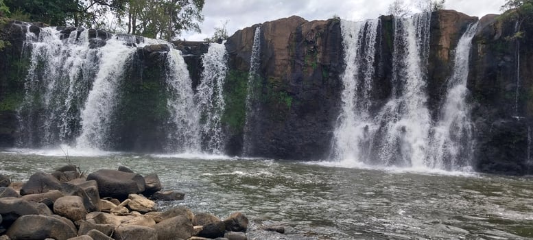 Beautiful scenic waterfall cascading over rocky cliffs surrounded by lush greenery under an overcast sky. photo