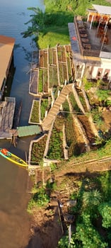 Aerial view of a wooden staircase leading to a riverbank with lush greenery, a house, and a boat docked by the water. photo