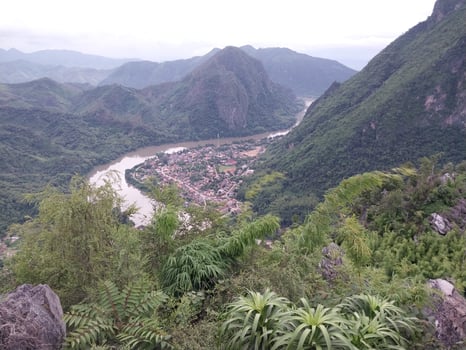 Scenic mountain landscape with a winding river and lush greenery surrounding a small village nestled in the valley. photo